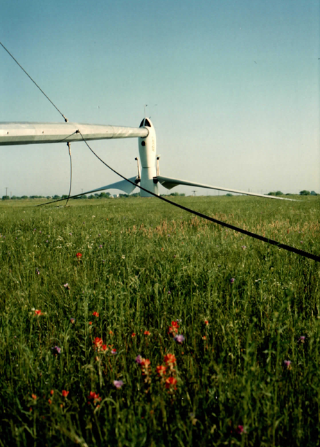Machine parked nose-down in the meadow for service — rotor, hub and nacelle all reachable without leaving the ground.