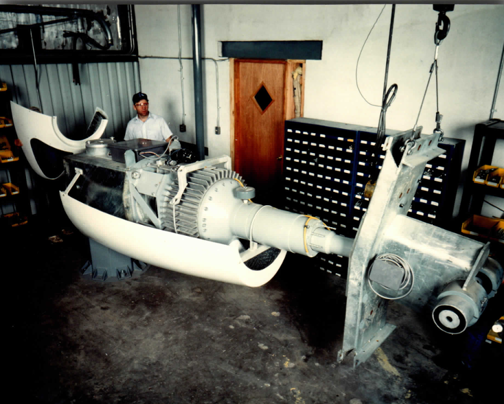 The complete drivetrain trial-assembled on the shop floor: generator frame in the nacelle cradle, output coupling and slip-ring stack toward the yaw plate — checked as one unit before the shells close around it.