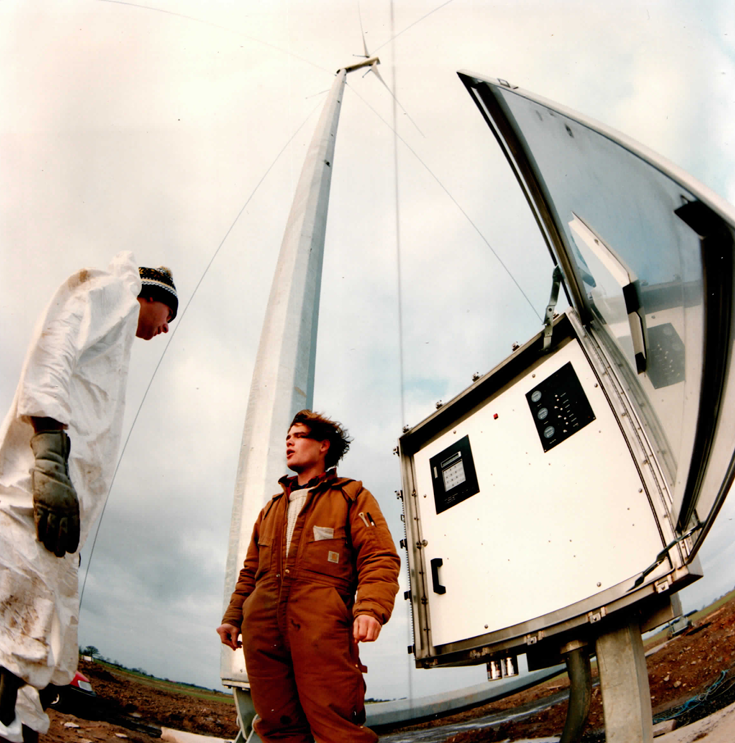 Commissioning crew at the base of an erected machine — the ground-level controller cabinet means no climb for setup or checks.